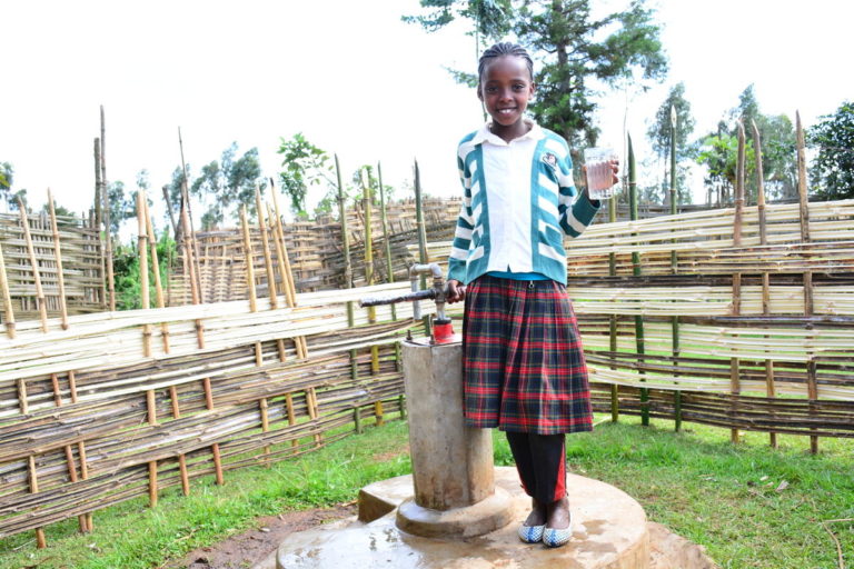 Atote Ware, age 10, grade 3, enjoys a glass of clean drinking water at a hand-drilled well in Hula ADP.